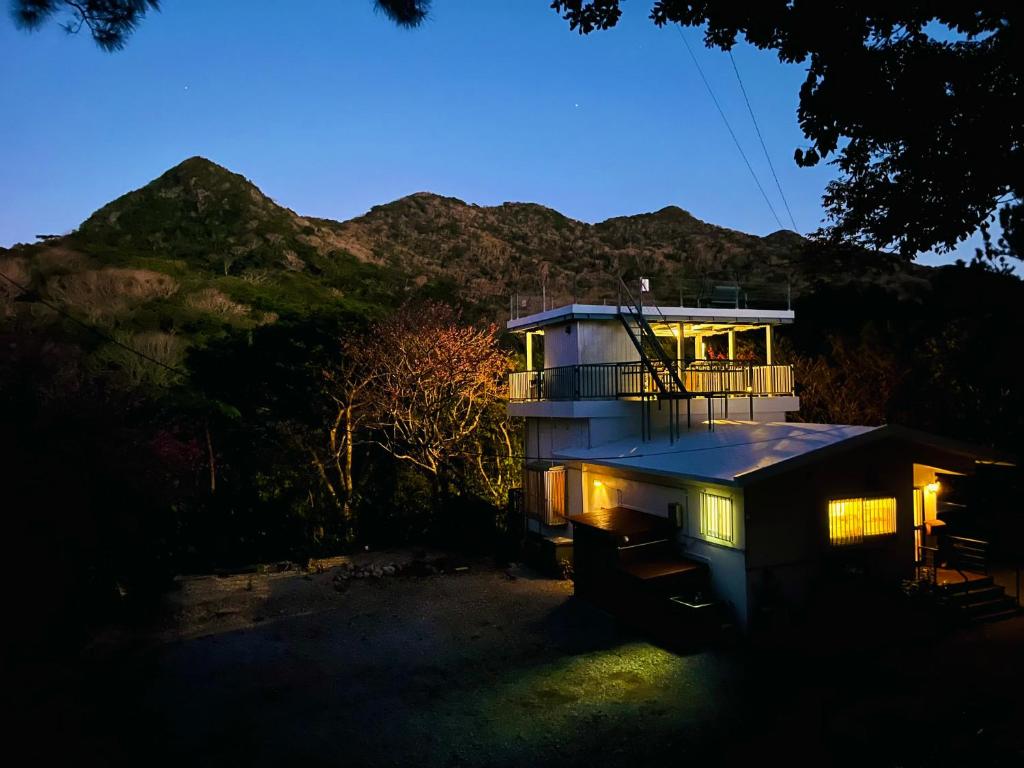 una casa illuminata di notte con montagne sullo sfondo di Lodge Crea a Ujimi