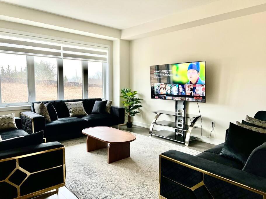 ein Wohnzimmer mit Sofas und einem Flachbild-TV in der Unterkunft Spacious 4BR Home near Hamilton Airport in Caledonia