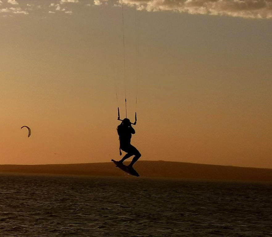 un homme pratiquant le kitesurf sur l'eau au coucher du soleil dans l'établissement Studio On Fairway, à Langebaan