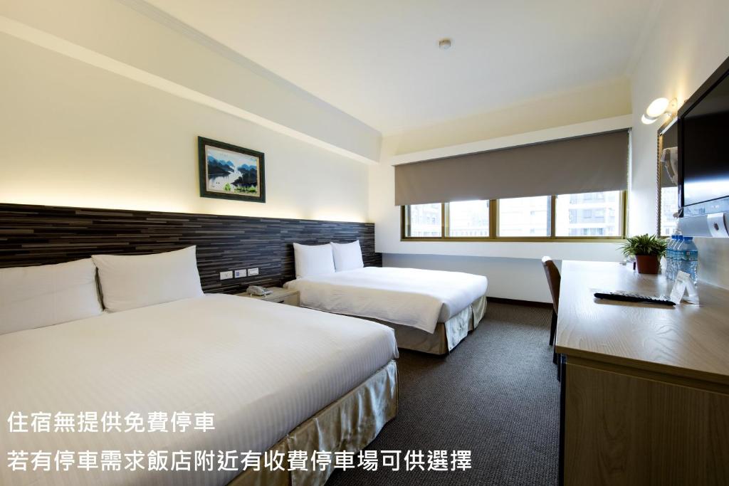 a hotel room with two beds and a desk at Ful Won Hotel in Taichung