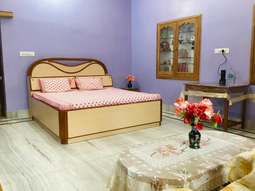 - une chambre avec un lit et une table ornée d'un vase de fleurs dans l'établissement Bikaner bliss - guest suite, à Bikaner