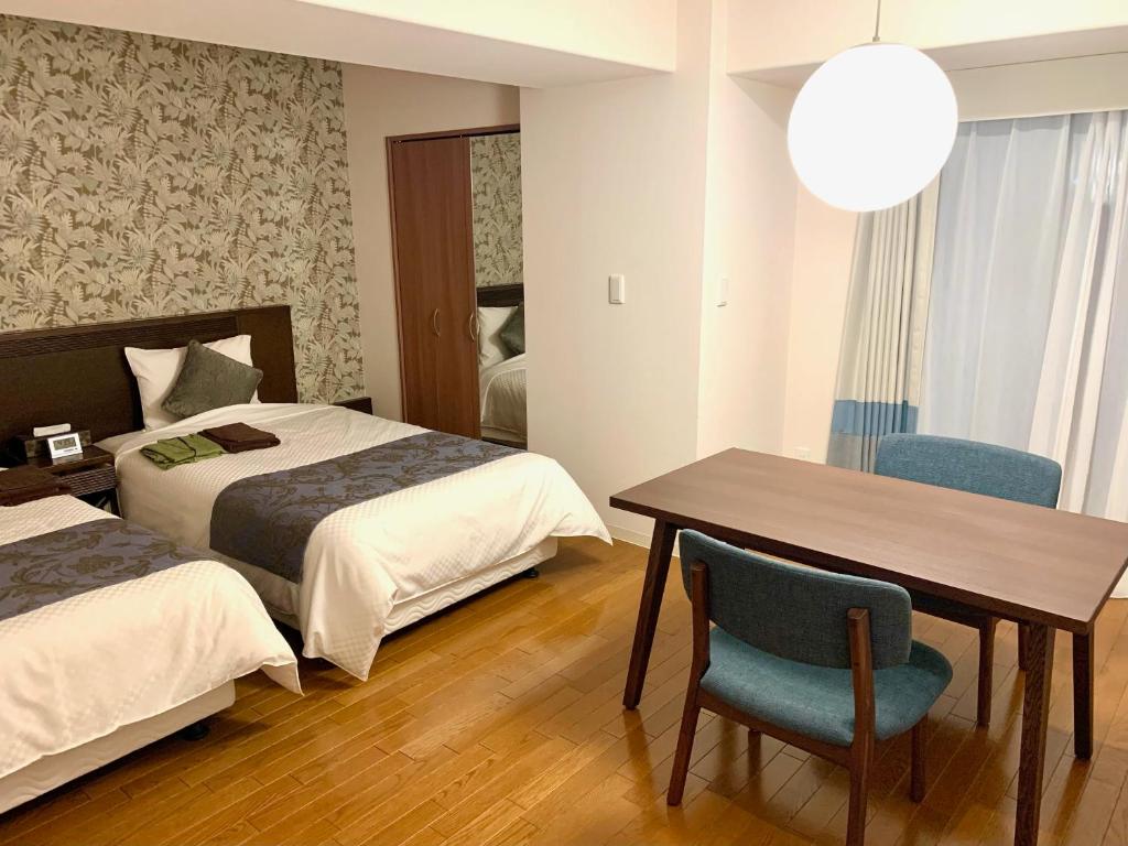 a hotel room with two beds and a table and chair at Hotel Global View Hakodate in Hakodate