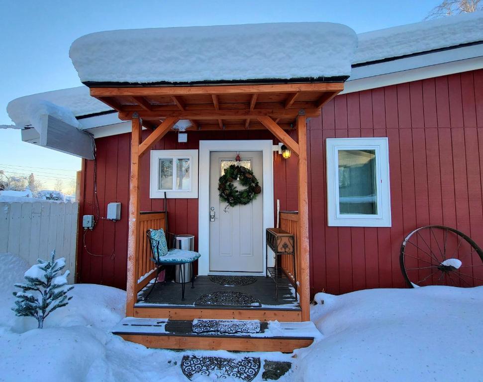 una casa roja con una puerta blanca en la nieve en A city studio, with a cabin-feel, for 1, en Fairbanks