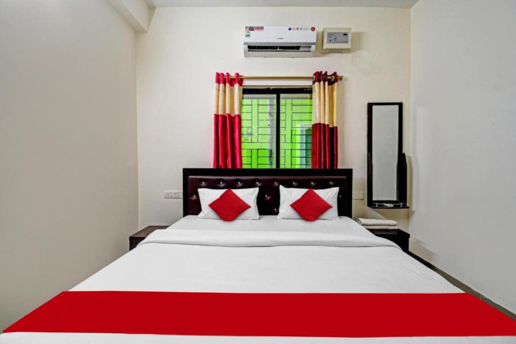 1 dormitorio con 1 cama blanca grande con almohadas rojas en Goroomgo SR Palace Bhubaneswar, en Bhubaneshwar