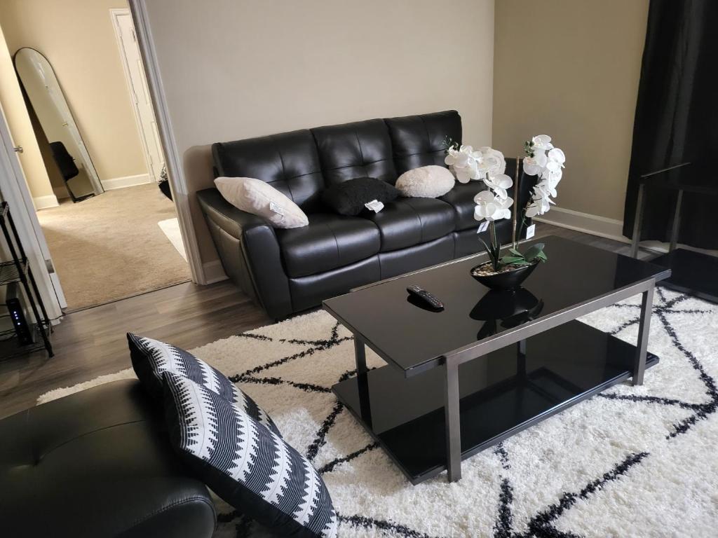 a living room with a black leather couch and a coffee table at kaysgroove in Alexandria