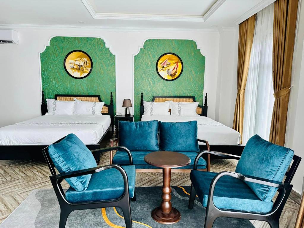 um quarto de hotel com duas camas e cadeiras azuis em Khách Sạn The One Hotel 1 em Cà Mau