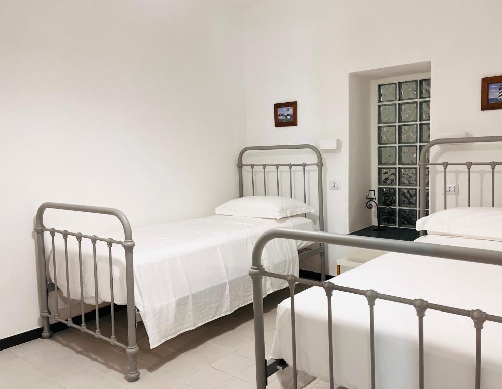 deux lits dans une chambre aux murs blancs dans l'établissement Splendida Casa - 50 metri dal mare, à Portoscuso