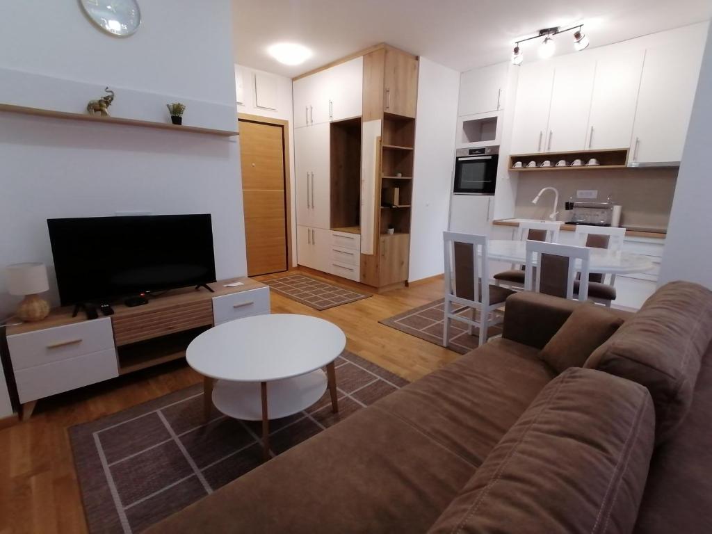 sala de estar con sofá, mesa y cocina en Milnik apartman, en Zlatibor