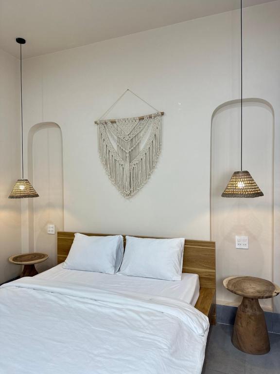 una camera da letto con un letto con due tavoli e un lampadario a braccio di Nhà Mer – Homestay đảo Phú Quý a Cu Lao Thu
