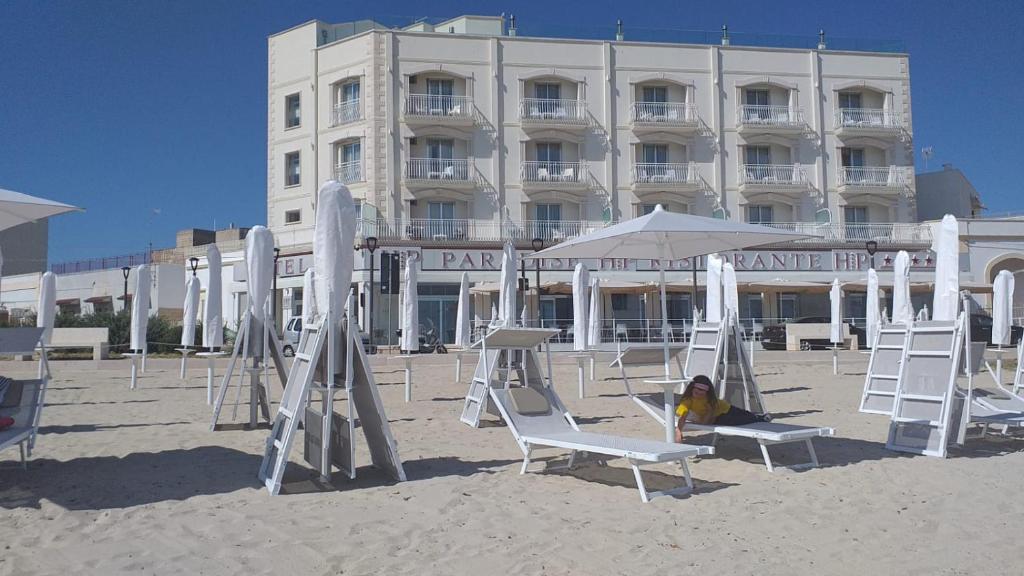 a woman sitting in chairs on the beach in front of a hotel at HOTEL PARADISE in Porto Cesareo