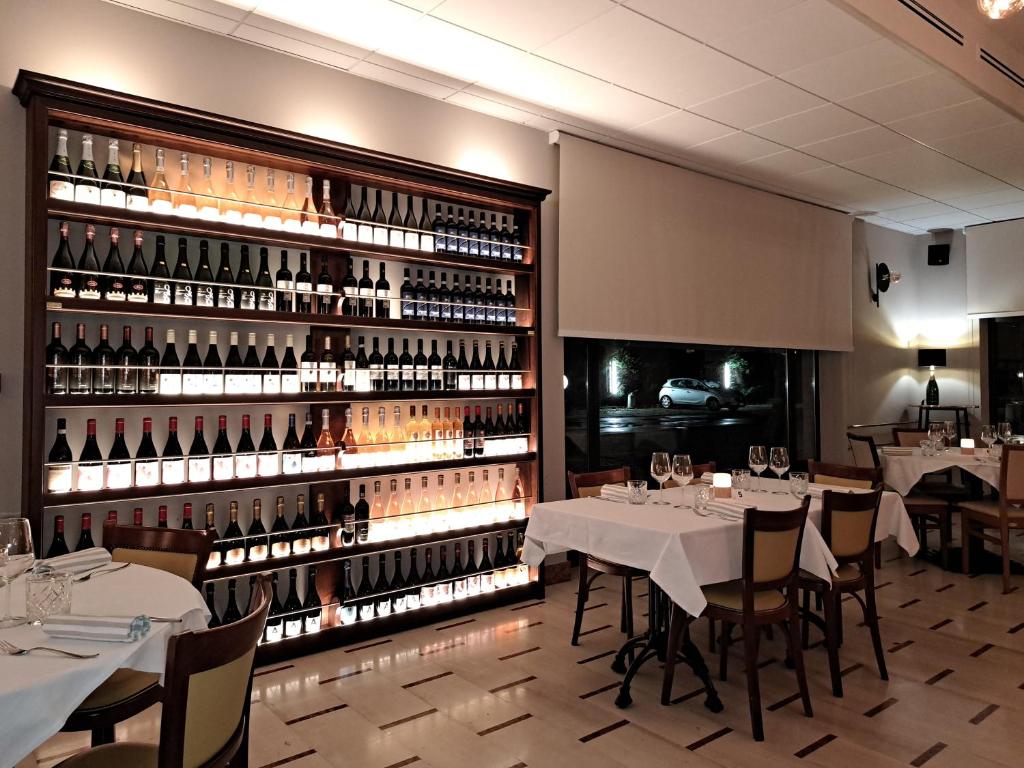 un restaurant avec des tables et un grand mur de bouteilles de vin dans l'établissement BRIXELLUM, à Brescello