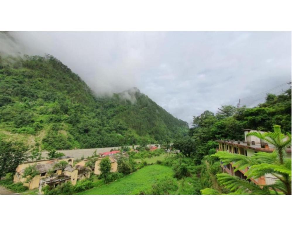 The Devdwar Yoga Resort, Uttarkashi في Uttarkāshi: اطلاله على جبل مع مدينه في المقدمه