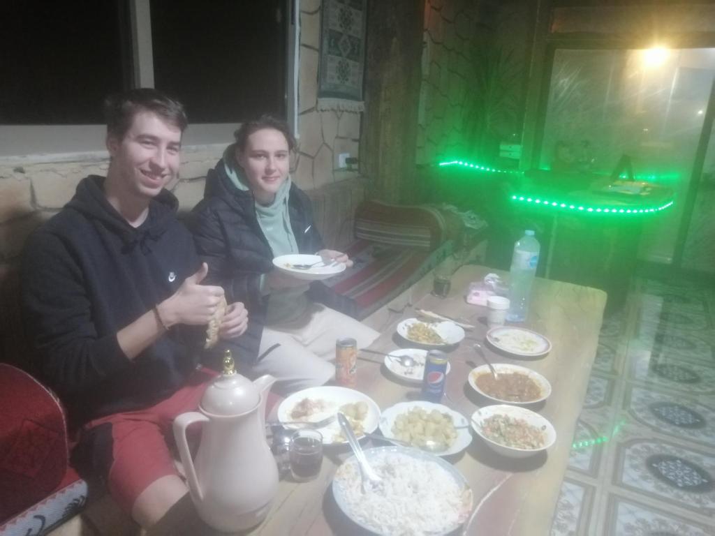 dos hombres sentados en una mesa con comida en Dana Nabil Ecu Camp House - Main Gate Dana nature reserve en Dana