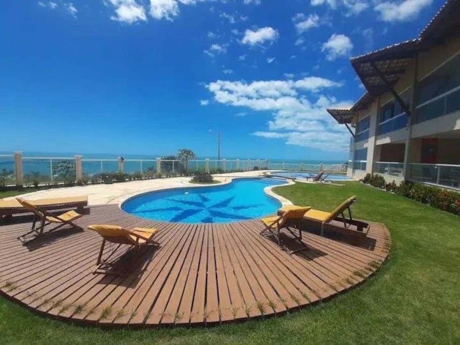 una terraza con sillas y una piscina en un edificio en Apart Canoa Quebrada vista mar- condominio fechado, en Aracati