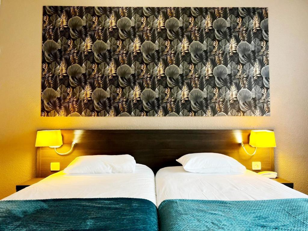 ジアンにあるBrit Hotel Confort Gienの壁に絵画が飾られた部屋のベッド2台
