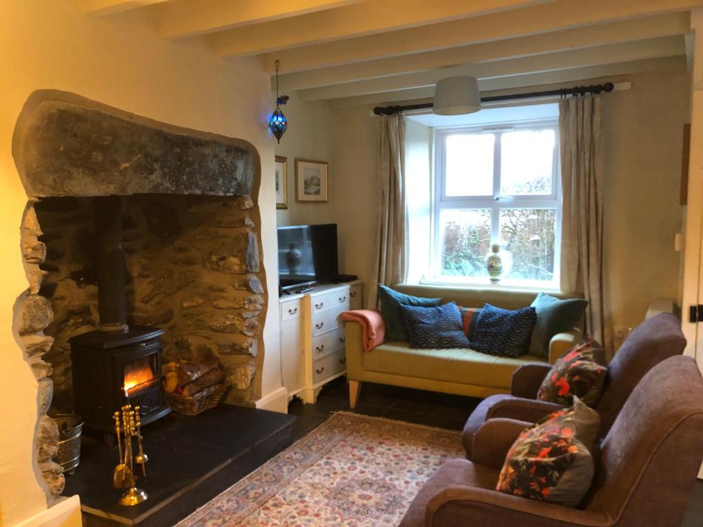 a living room with a stone fireplace and a couch at 1 Penygroes in Penmachno