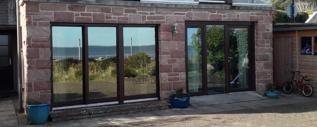 a brick building with windows with a view of the beach at Ceol Na Mara (Music of the Sea) in Rosemarkie