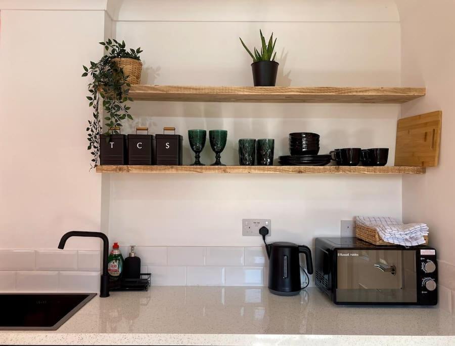 a kitchen with a counter with a microwave and shelves at Cabin de la Paix in Hadleigh