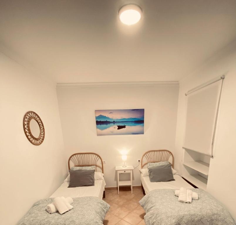 Cette chambre comprend deux lits et une table avec un miroir. dans l'établissement Vivienda 2 dormitorios Churriana-Aeropuerto, à Malaga