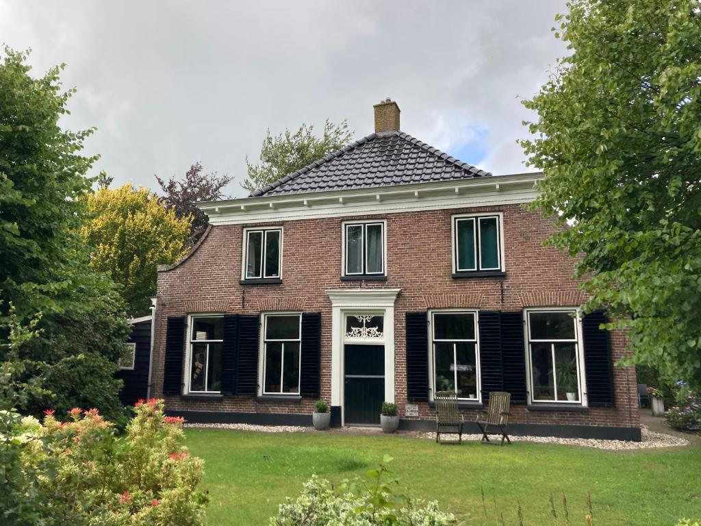 ein altes Backsteinhaus mit grüner Tür in der Unterkunft De Lindehoeve Appartement de Deel in Vledder
