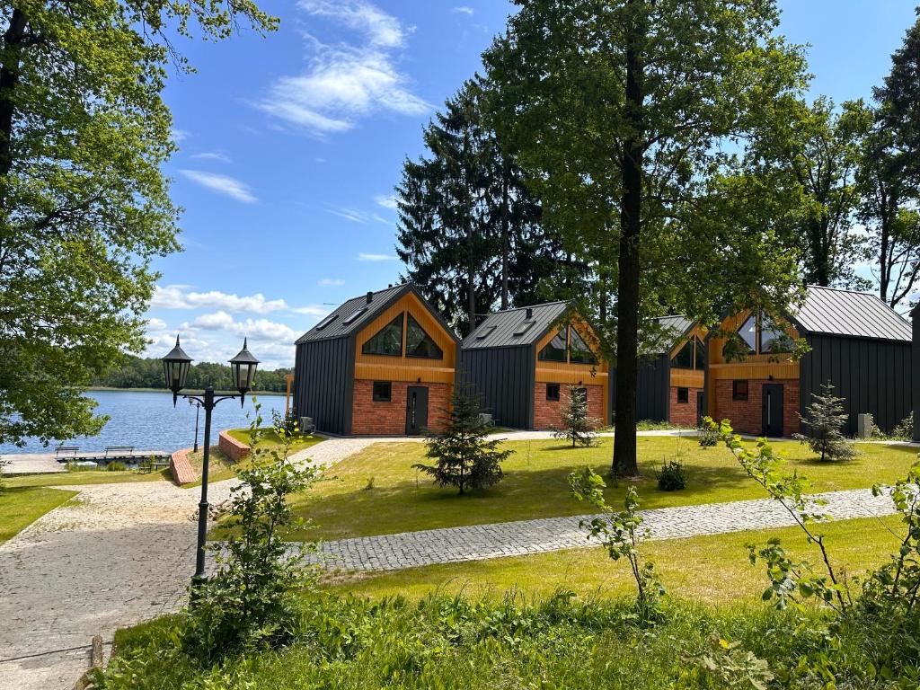 een rij huizen met bomen en water bij Domki nad jeziorem Złoty Potok in Kalinowo