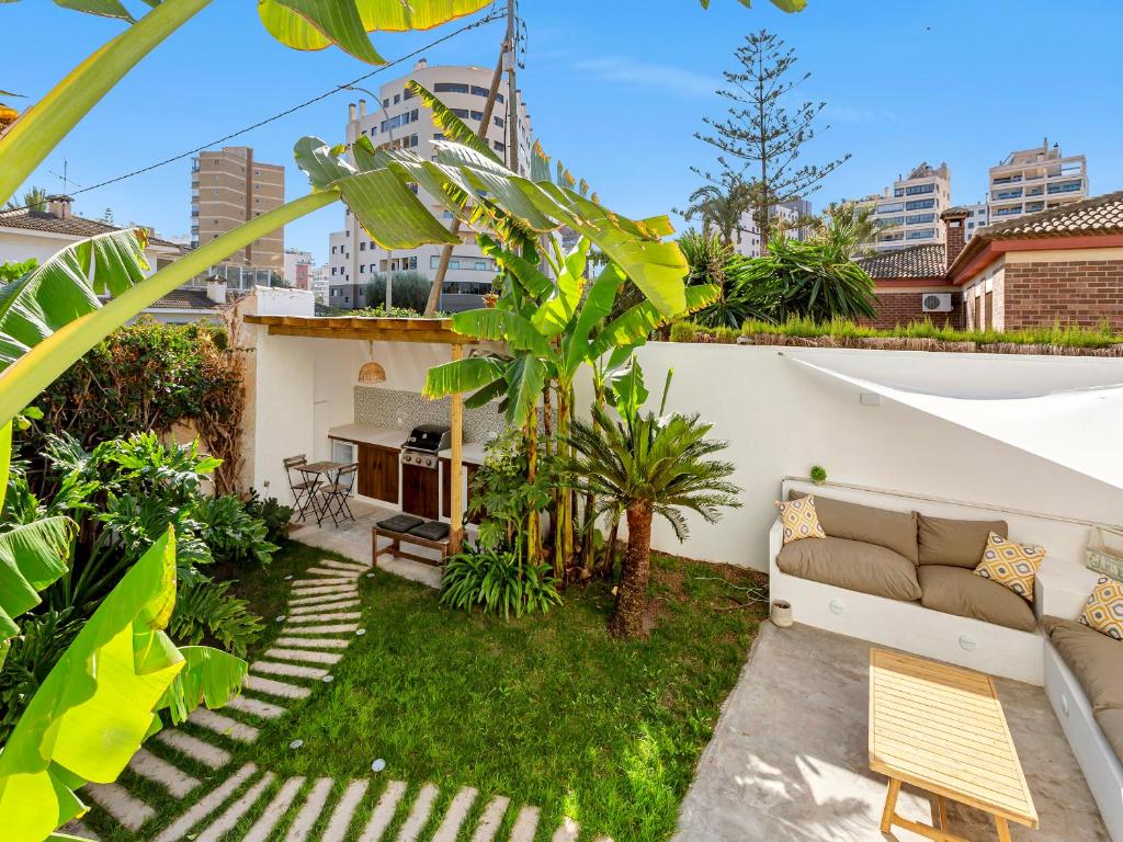 un pequeño patio trasero con sofá y césped en Mediterranean tropical house, en El Campello