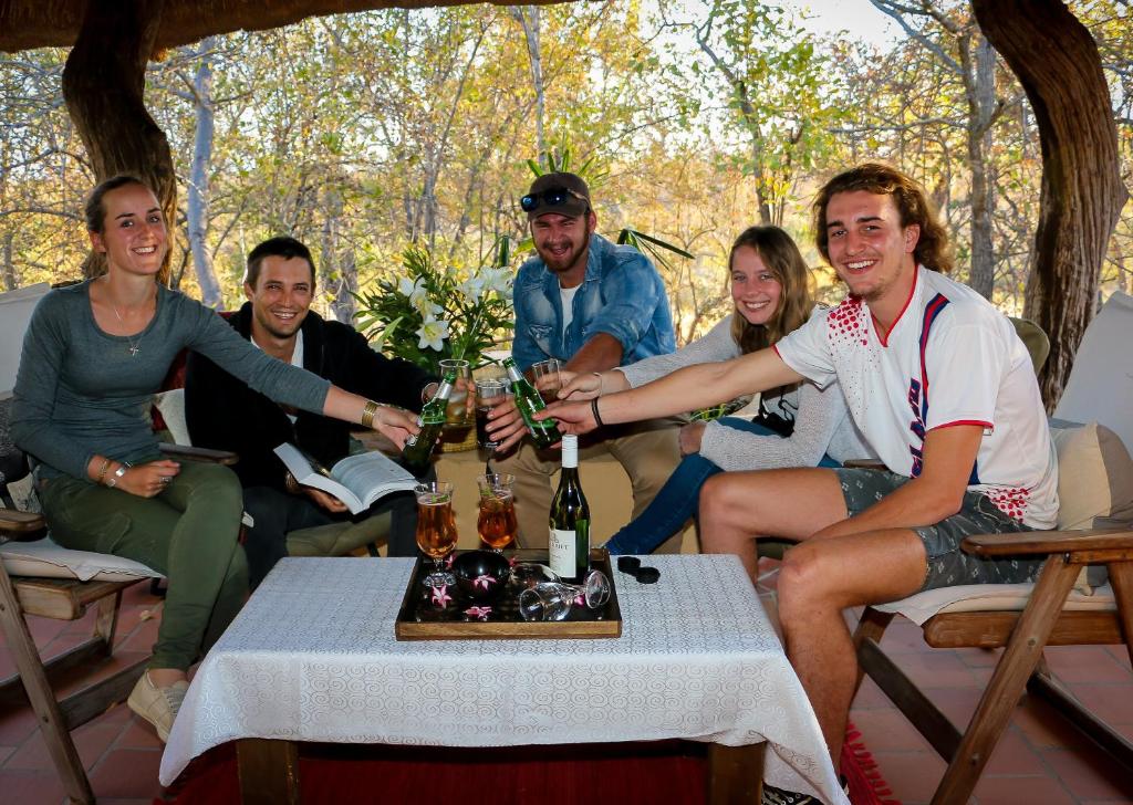 um grupo de pessoas sentadas à volta de uma mesa com garrafas de vinho em Tamanini Timbavati Lodge em Hoedspruit
