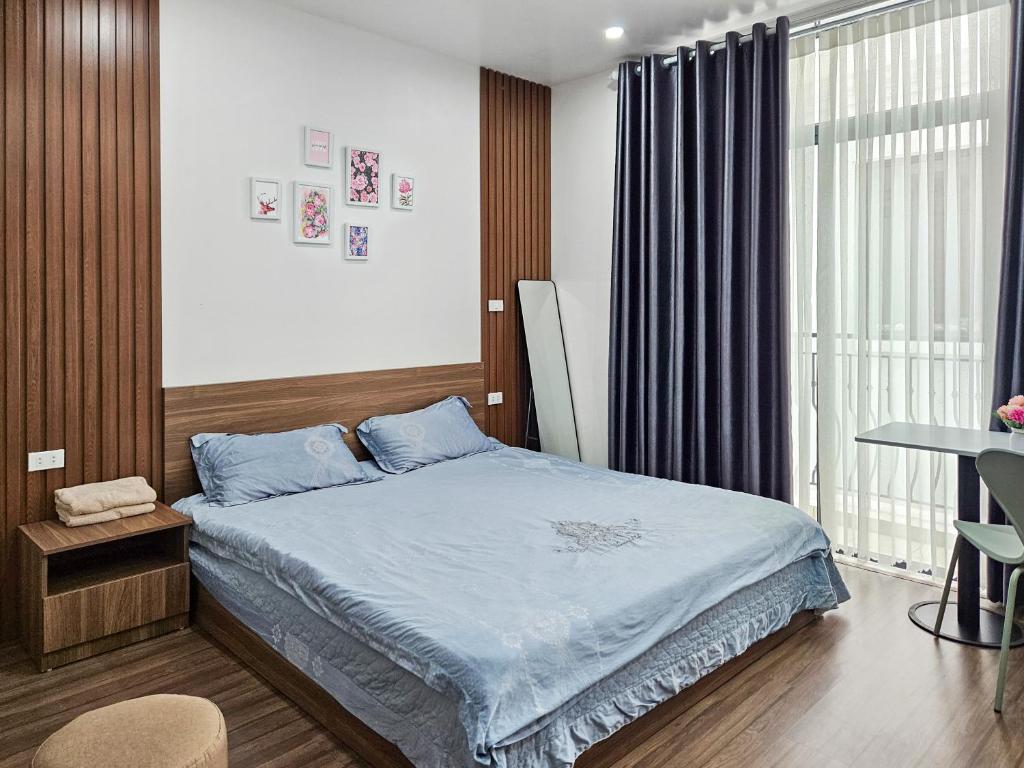 1 dormitorio con cama con sábanas azules y ventana en CHLOE'S SERVICED APARTMENT - VINHOMES MARINA, en Xóm Niêm