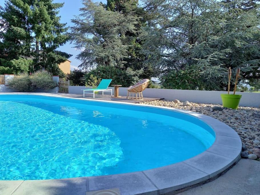 une grande piscine bleue avec une chaise et un oiseau dans l'établissement L'échappée verte, à Champdieu