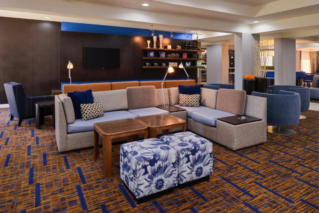 eine Lobby mit einem Sofa und Stühlen sowie einem TV in der Unterkunft Courtyard by Marriott Milwaukee North/Brown Deer in Brown Deer