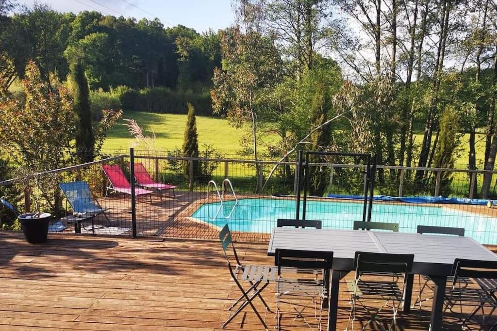 um pátio com uma mesa e cadeiras ao lado de uma piscina em Maison architecte en bois avec piscine et jacuzzi em Pruillé-lʼÉguillé