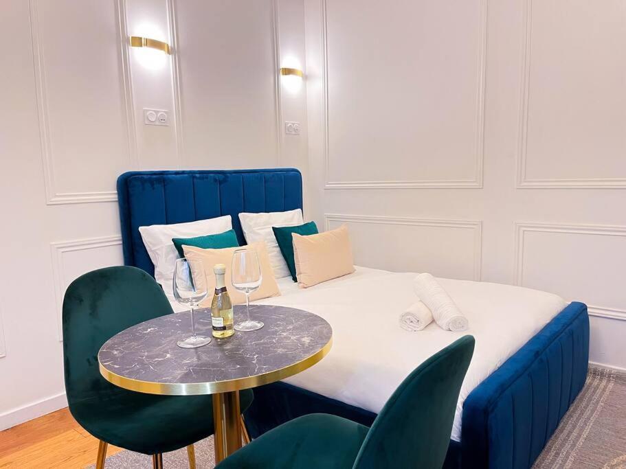 - un lit bleu avec une petite table et des chaises dans l'établissement Studio Chic Montmartre Opéra, à Paris