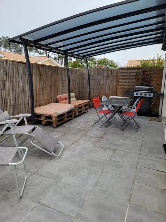 een patio met stoelen, een tafel en een grill bij Villas Floryanne - bassin arcachon in Audenge