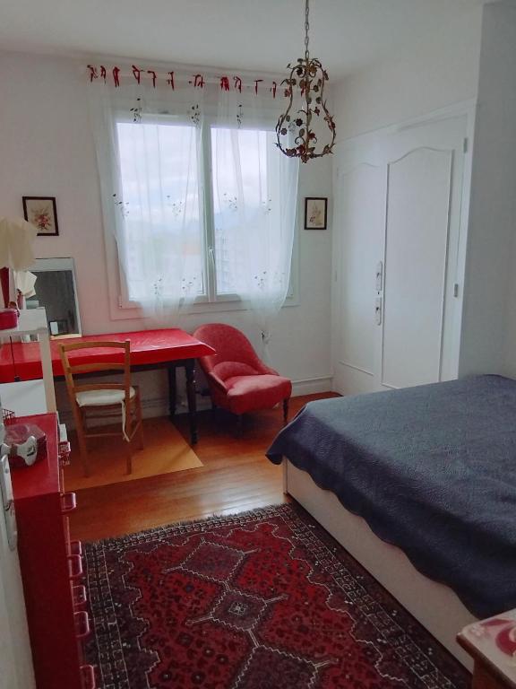1 dormitorio con 1 cama, 1 mesa y 1 silla en chambre rouge, en Grenoble