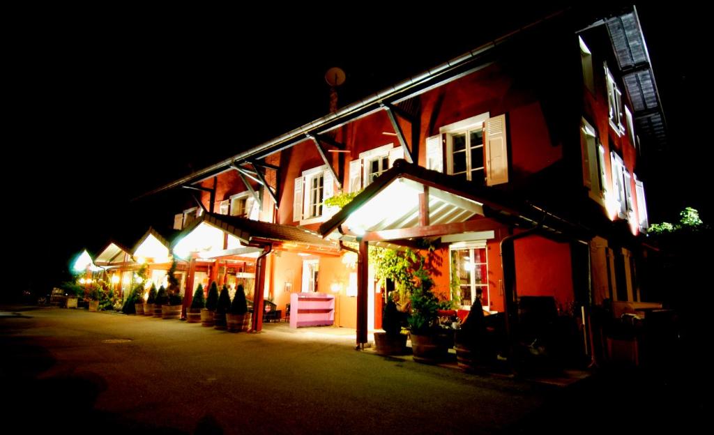 una fila de edificios por la noche con gente de pie fuera en Auberge De Maison Rouge en Vétraz-Monthoux