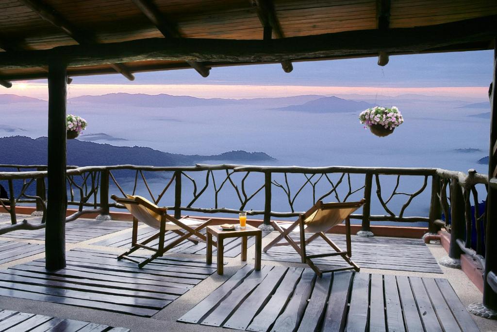 a table and chairs on a deck with a view of mountains at Phu Pha Nam Resort in Dan Sai