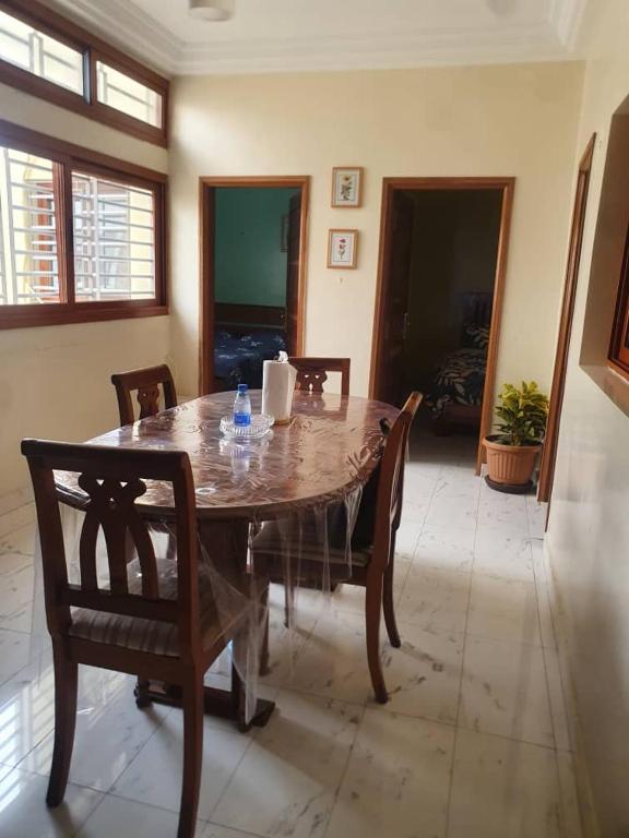 uma mesa de madeira e cadeiras numa sala de estar em Residence Hadja 03 em Dakar