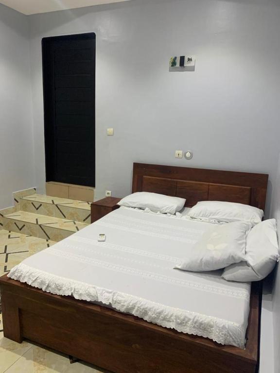 een bed met witte lakens en kussens in een kamer bij BELLA HOME in Cotonou
