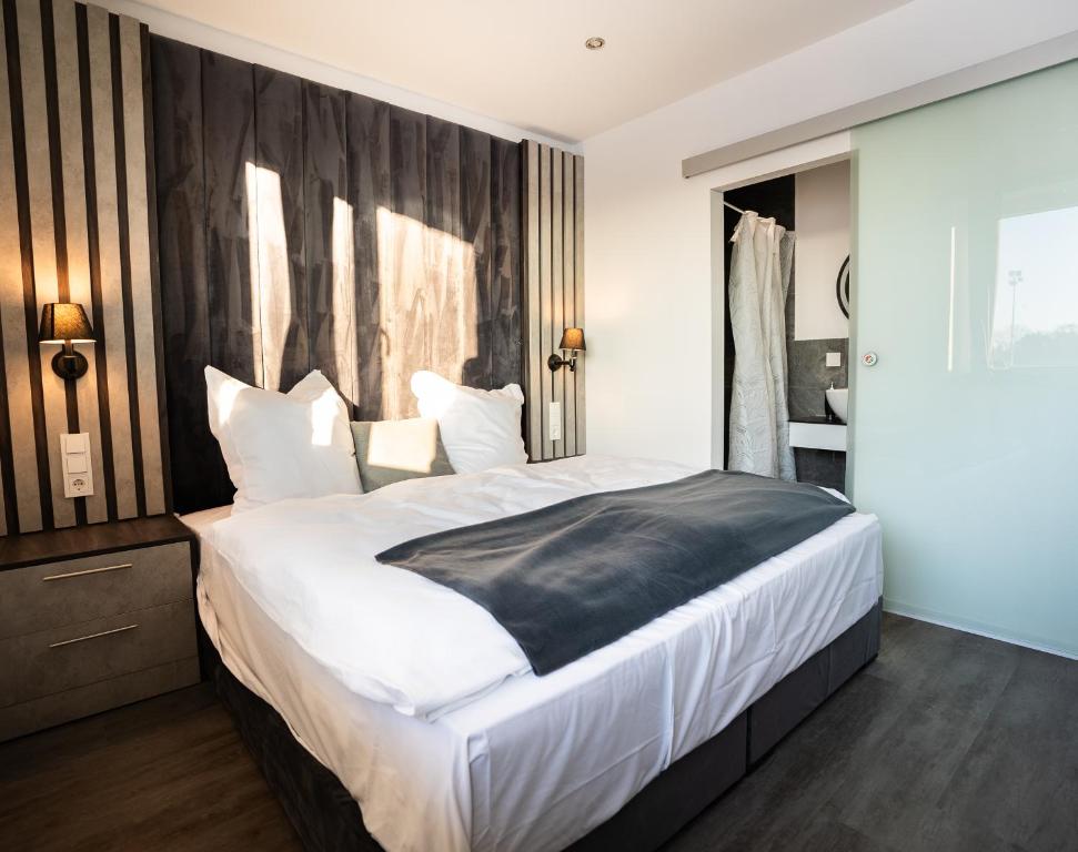 um quarto com uma cama grande e uma cabeceira preta em Hotel We Wellness em Adendorf