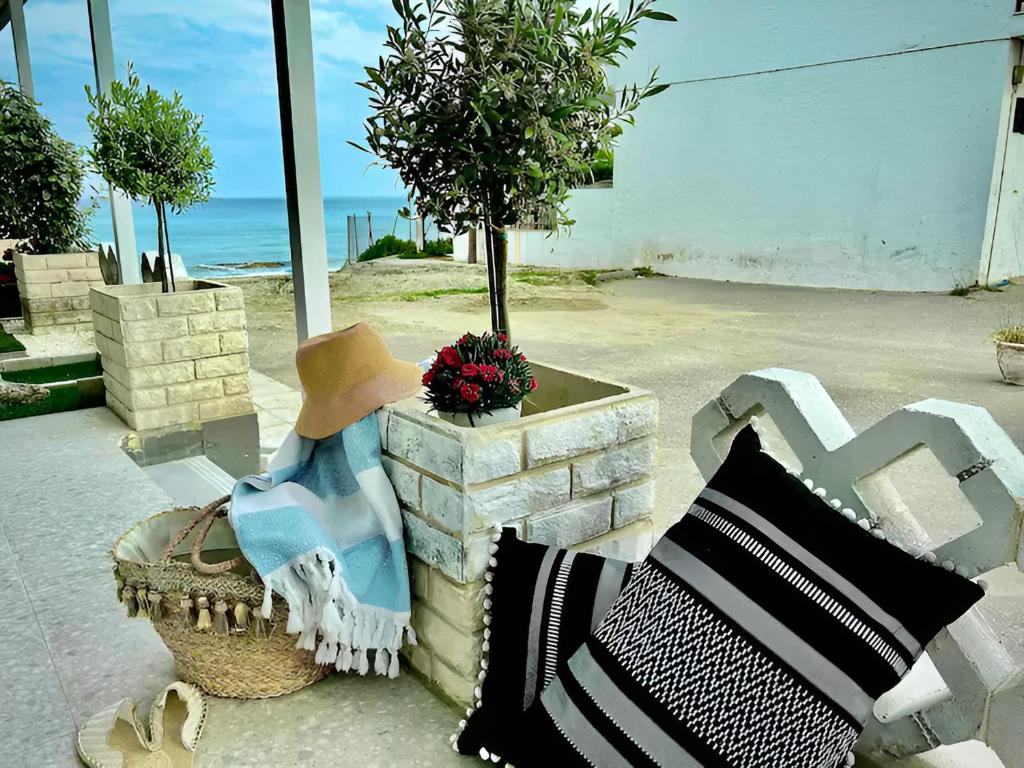 a bench with a hat and pillows and a tree at House by the sea suite 2 in Skála Foúrkas
