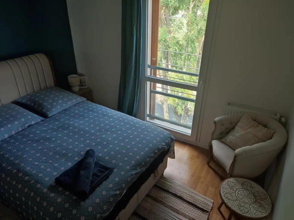 una camera con un letto e una sedia e una finestra di A 10 mins d'aéroport d'ORLY chambre de 12 m2 lumineuse chaleureuse ad Athis-Mons
