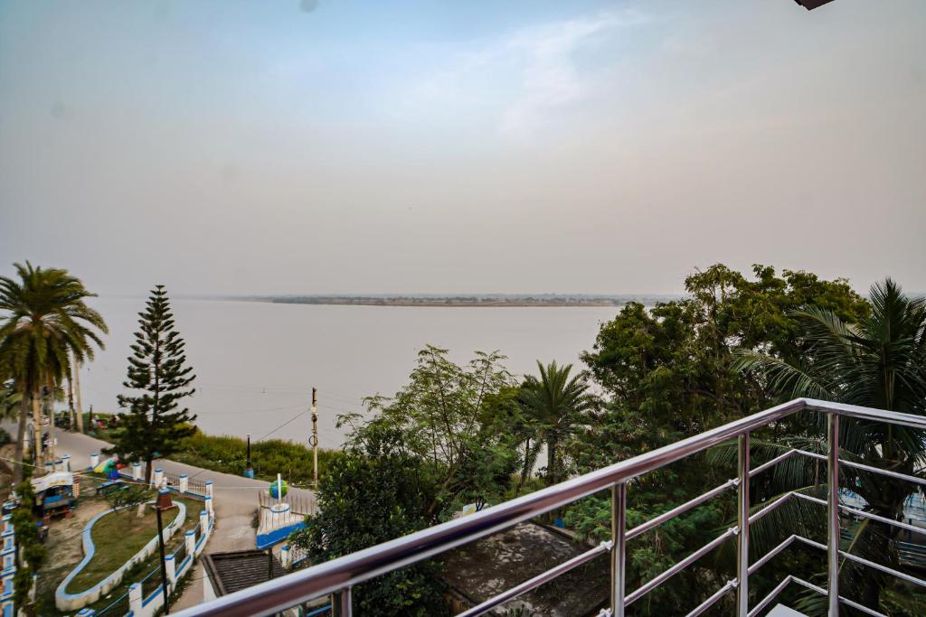 uma vista a partir da varanda de um resort com palmeiras em River Leaf Inn Taki em Hāsnābād