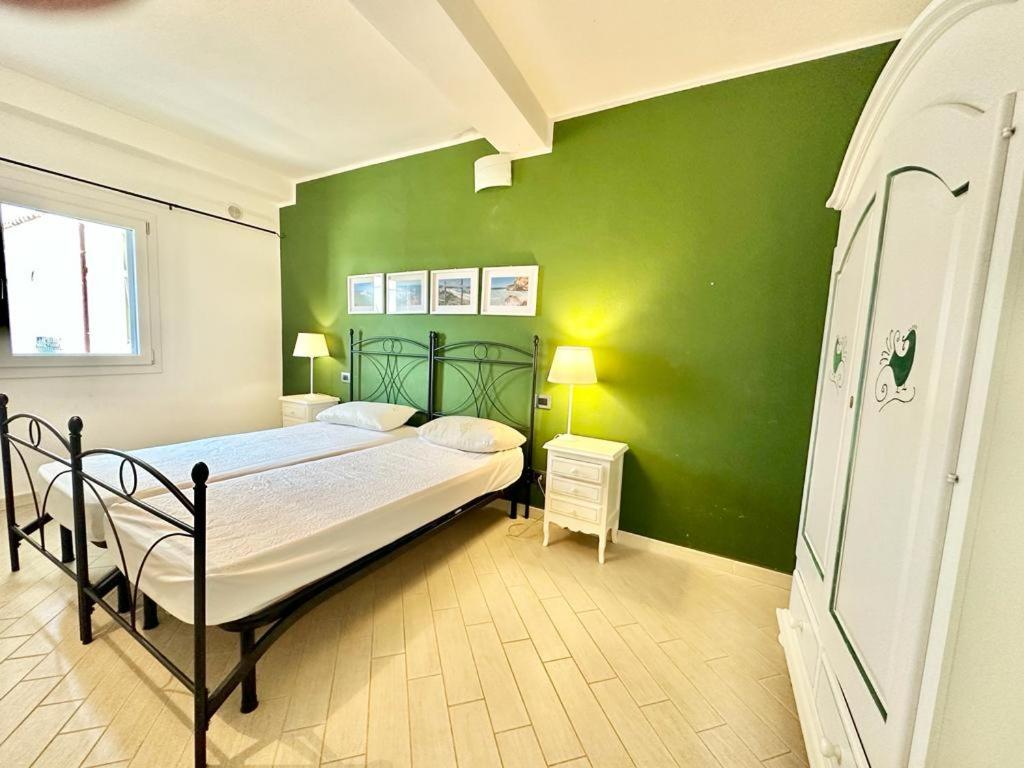 a bedroom with a bed and a green wall at Lux Limone - Appartamenti in residence con piscina in Orosei
