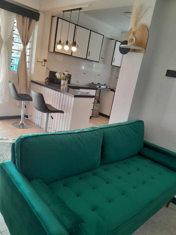 a green couch in a living room with a kitchen at Nomads Nest Fiji in Suva