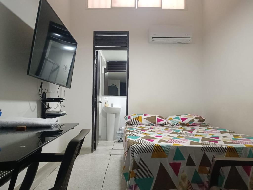 Schlafzimmer mit einem Bett, einem Schreibtisch und einem TV in der Unterkunft Apto 101 in Cúcuta
