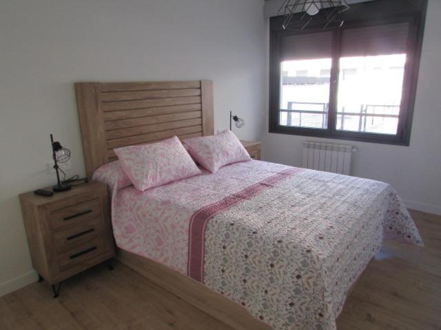 een slaapkamer met een bed met roze kussens en een raam bij VUT Mar de Llanes in Llanes