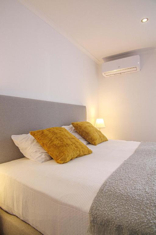 a bedroom with a bed with two pillows on it at Pine House - Faro Airport, Beach and City Center in Faro