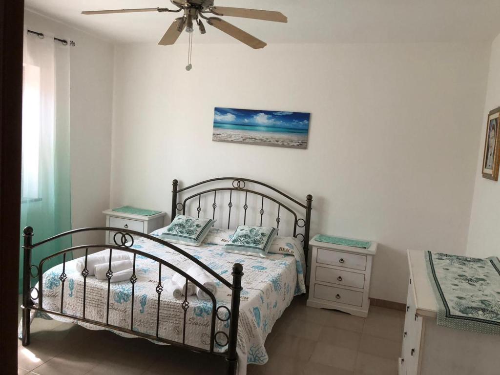 a bedroom with a bed and a ceiling fan at Green Apartment in La Maddalena