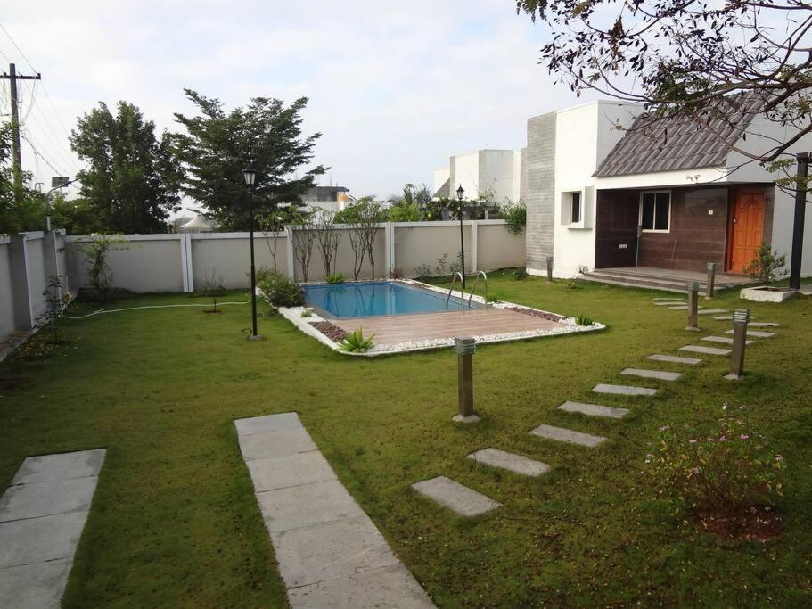 un patio trasero con piscina y una casa en Charm Ville - Villa with Nature in Hosur en Hosūr