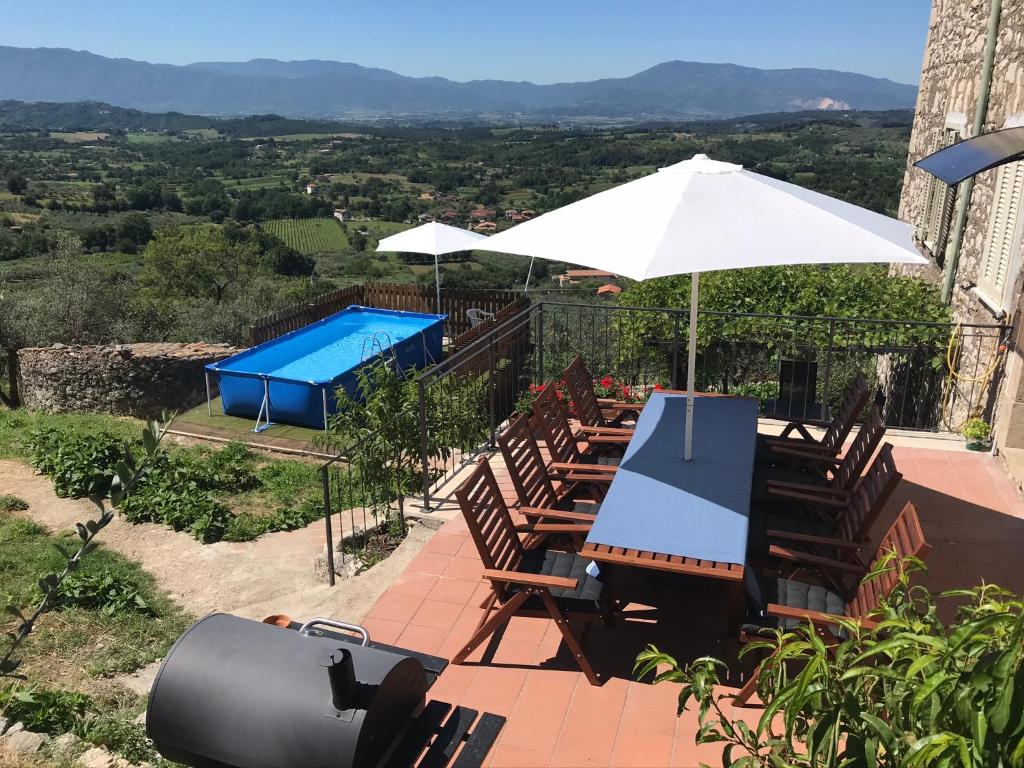 un patio con sillas, una sombrilla y una piscina en House near Rome with Beautiful Views and Pool, en Piglio
